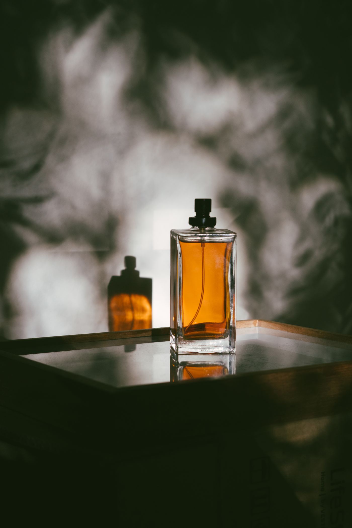 Amber cologne bottle on a mirrored tray in warm light
